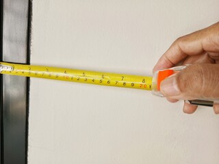 A man measures the surface of a wall with a measuring tape.