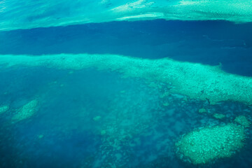 Aerial view of submerged reefs (green color) and surface clear waters (blue color) at Great Barrier...