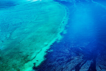 Aerial view of submerged reefs (green color) and surface clear waters (blue color) at Great Barrier Reef, the world's largest coral reef system in the Coral Sea near Whitsunday Island. Australia. 2020