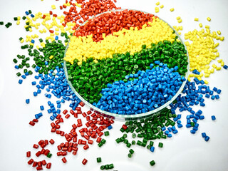 various colors of masterbatch granules in glass containers, polymer carrying resin and pigments poured in white background, suitable for product catalog design of industrial plastic company profile