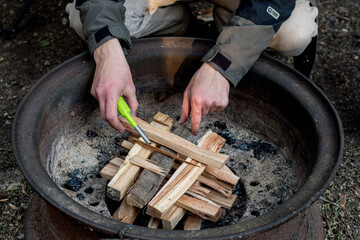 Starting a campfire in a firepit with kindling. Camping lifestyle.