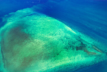 Aerial view of submerged reefs (green color) and surface clear waters (blue color) at Great Barrier Reef, the world's largest coral reef system in the Coral Sea near Whitsunday Island. Australia. 2020