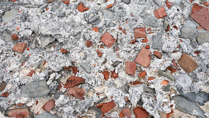 Wall background with textured gray fossil shaped stones and old brick pieces in cement