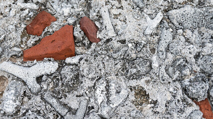 Wall background with textured gray fossil shaped stones and old brick pieces in cement