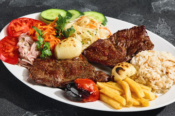 Beef steaks with grilled vegetables, french fries, and rice, bright lighting, overhead composition
