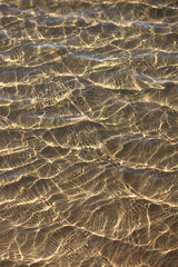 Mesmerising natural liquid patterns of crystal clear ocean water glistening in the shallows of an...