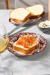 Brioche with butter and red caviar in bright natural light, overhead composition for modern menu