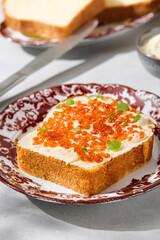 Brioche with butter and red caviar, bright lighting, closeup composition