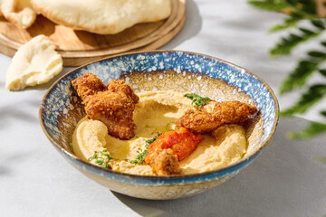 Hummus with chicken strips and pita in bright natural light, overhead composition