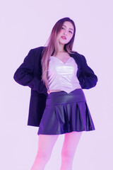 Asian pretty young woman model pose confident under purple neon lighting wearing silver corset top black pleated leather skirt black jacket expressing trendy streetwear creating bold fashion in studio