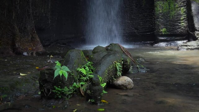 Stone sculpture of a woman lying by a waterfall, Sumampan, Bali, Indonesia.