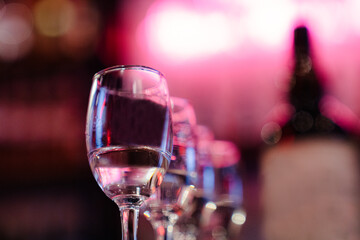 Elegant Wine Glasses in Colorful Bar Light with Bokeh Background