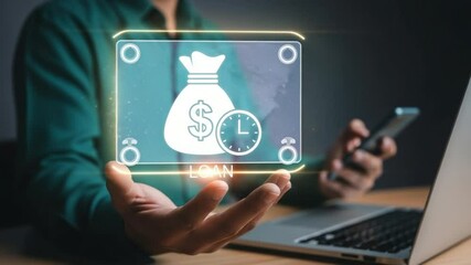 Person holding loan graphic over hand while using a phone and laptop on a wooden desk - Powered by Adobe