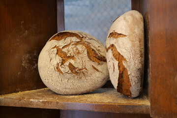 Artisan bread loaves resting on a wooden shelf in a bakery