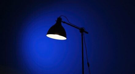 A sleek black desk lamp illuminating a deep blue wall, creating a serene atmosphere for work or relaxation