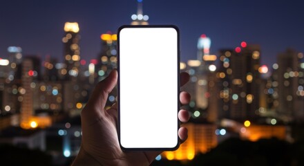 Hand holding smartphone with blank screen against blurred city skyline at night.