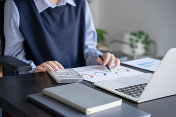 Asian businesswoman doing paper work with pen laptop calculator