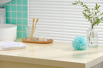 Fresh mint-tiled bathroom with a modern sink, folded towels, brush set and bath puff. Clean surface area is left blank for inserting design elements or cosmetic mockups.