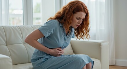 Woman in pain, sitting on couch