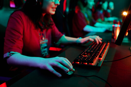 Teenage girls team using gaming computers and wearing headsets, focusing on playing esports together in competitive environment, multiethnic group participating in online tournament - Powered by Adobe