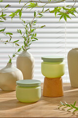 Soft lighting on green containers, amber bottle, and ceramic vases on a wooden counter. Designed...