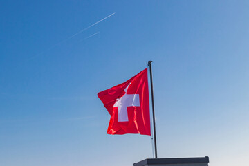 Red Swiss flag over the blue sky background