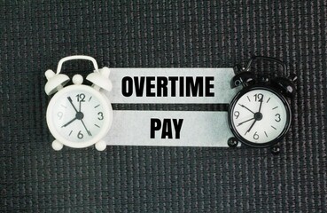 two clock bells and a tape with the words Overtime pay. the concept of overtime or payment by time