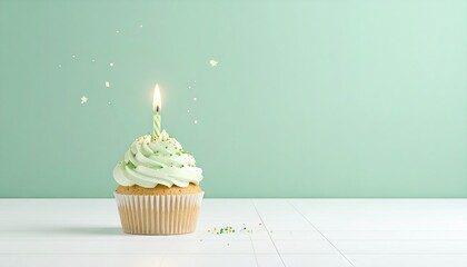 Single Lit Birthday Cupcake with Green Frosting and Sprinkles on White Wooden Table with Green Background