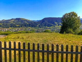 A wooden fence in the middle of a grassy field with mountains in the background
