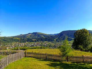 A grassy field with a wooden fence in front of a mountain range