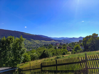 A wooden fence in the middle of a grassy field with mountains in the background