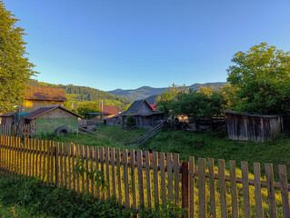 A wooden fence in front of a small village in the mountains