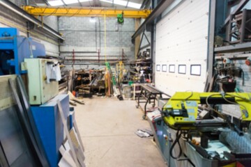 Featuring bright yellow metal-cutting band saw standing in workshop with crane hoist and rod racks