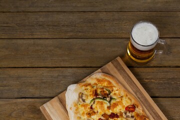 Fresh pizza with beer glass served on wooden table