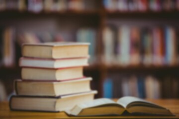 flat design is showing stack of hardcover books, open book on wooden table before blurred bookshelf