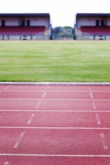 Flat design showing red running track lanes filling frame, white lane markers, grass field, stands © vectorfusionart