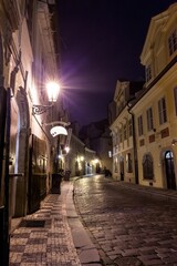 Flat style cobblestone street is glowing at night, featuring lanterns, shutters and signage bracket