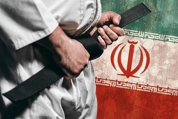 Fotobehang Vechtsport Midsection of martial artist tying belt against Iranian flag  © vectorfusionart