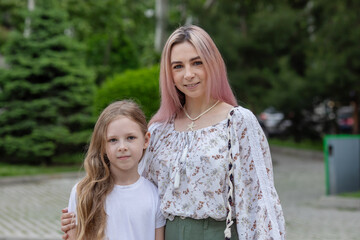 A woman with pink hair and a child with long hair pose for a picture