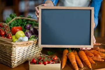 Fototapeten Woman holding board in front of vegetables © vectorfusionart