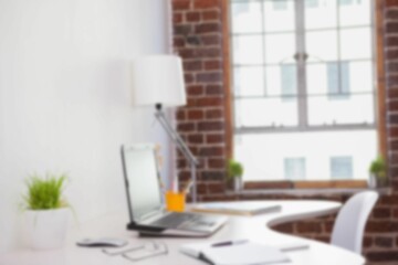 Defocused image of laptop on desk in office