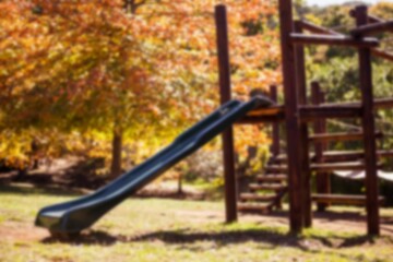 Wooden playground structure is featuring green slide and ladder in flat design under autumn trees