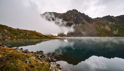 Morning mountain lake with misty clouds reflecting the natural landscape