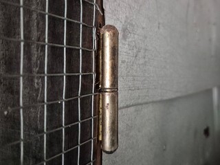 Close-up of an Old Metal Hinge Attached to a Wire Mesh and Wooden Frame
