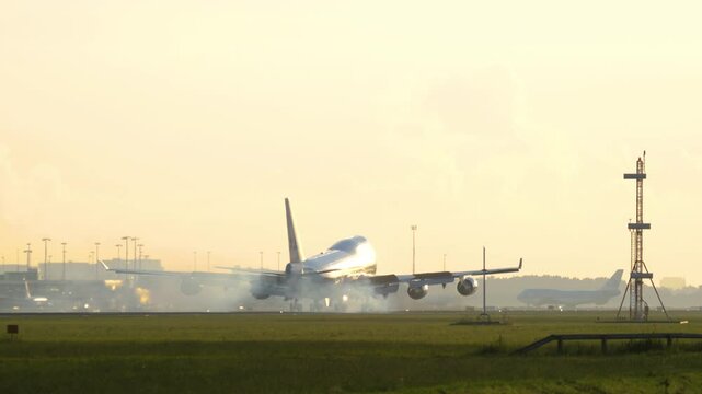Wide body airliner landing and touching the runway at Amsterdam Airport. Airplane in backlight