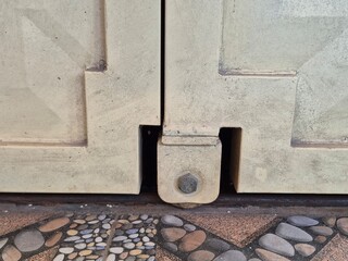 Close-Up of Sliding Gate Roller and Bolt on Track Above Decorative Stone Floor