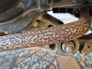 Close-up of Rusty Motorcycle Exhaust Pipe with Corrosion Spots Under Vehicle Frame