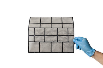 A technician's hand holds a air conditioner filter dusty isolated with clipping path on white background. preparation for maintenance and cleaning.
