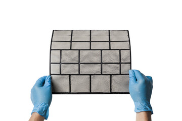 A technician's hand holds a air conditioner filter dusty isolated with clipping path on white background. preparation for maintenance and cleaning.