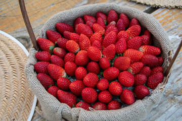 A basket full of strawberries displays charming simplicity: fresh red fruits on rustic wicker,...